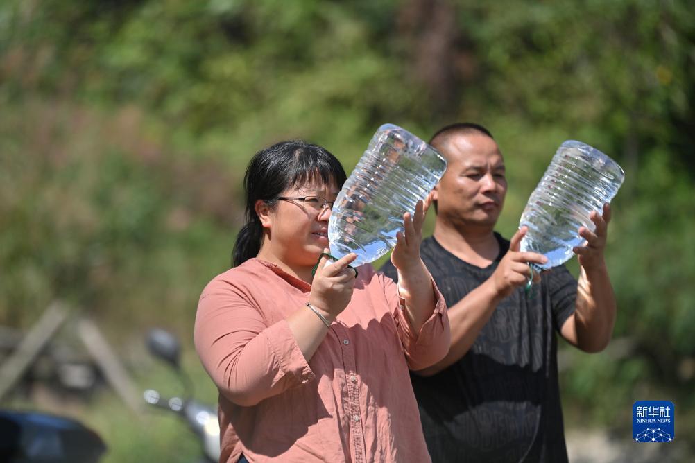 楊寧（左）在查看村民剛剛采集的水樣，為山泉水引水工程做準(zhǔn)備（10月8日攝）。新華社記者 黃孝邦 攝